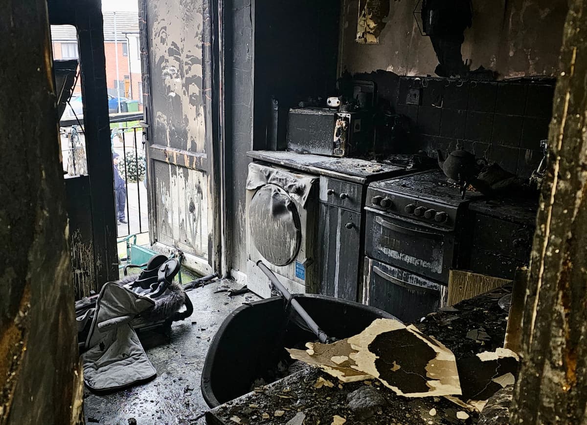 The kitchen area of the maisonette showing blackened walls, appliances and other damaged items.