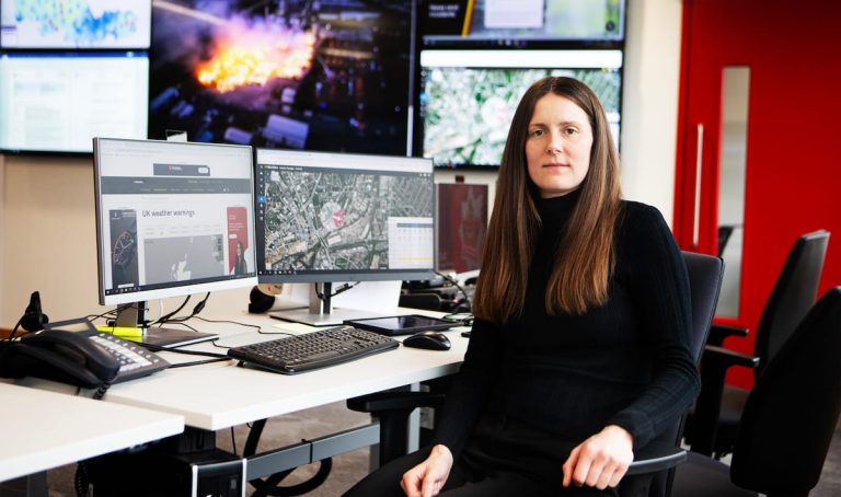 Hannah Spencer sat at her desk in the incident room with various screens and monitors behind her showing information and images.