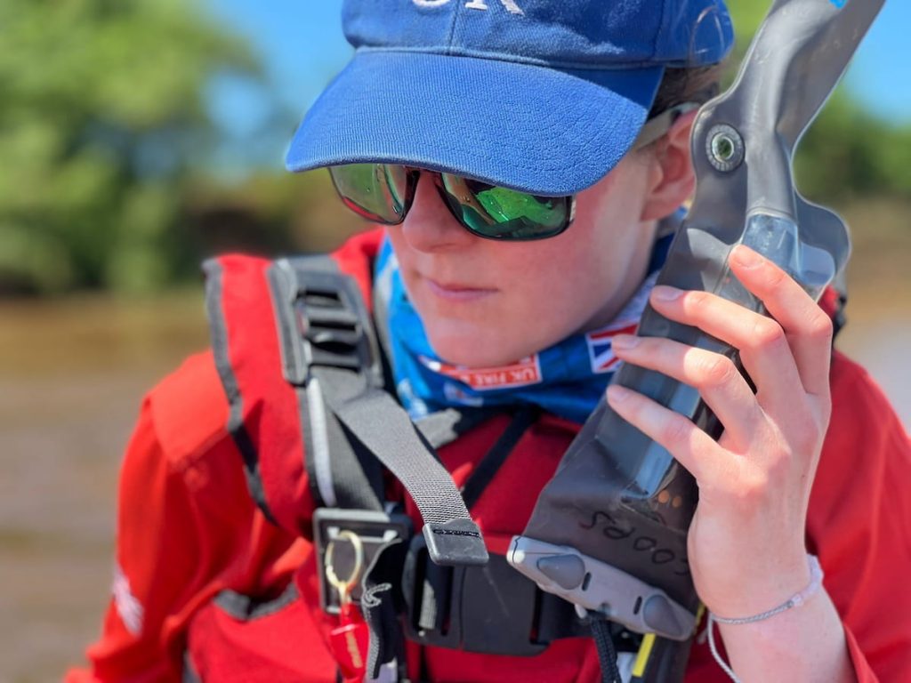 Hannah in ISAR uniform, hat and wearing sunglasses using a radio