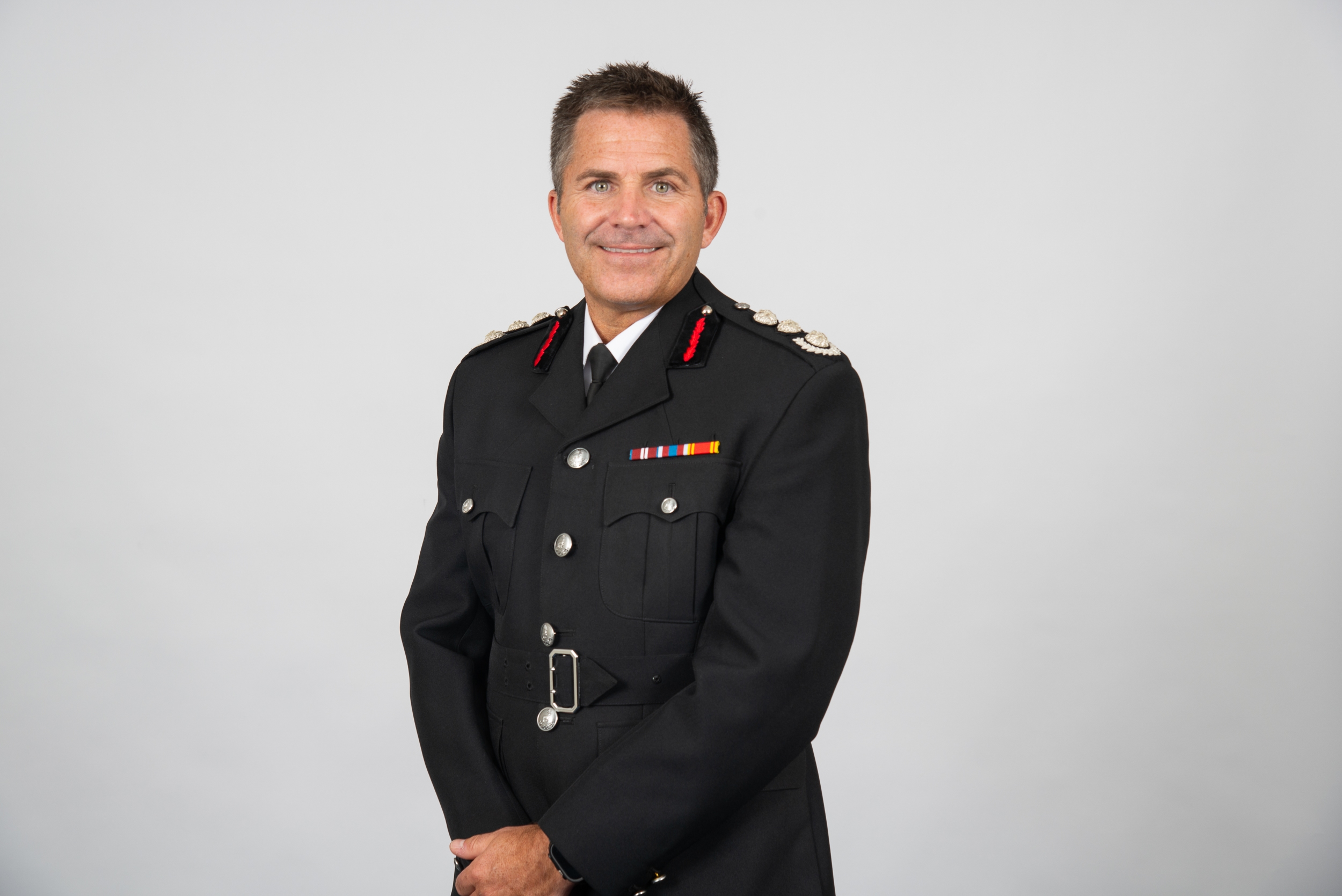 Chief Fire Officer Simon Tuhill is photographed behind a grey background.