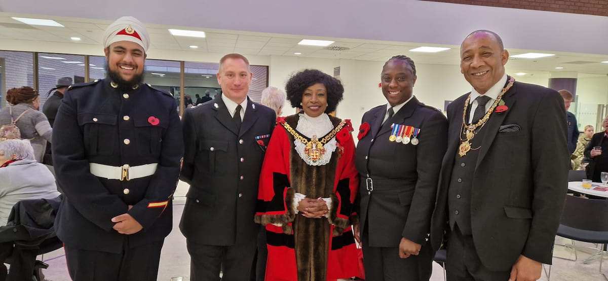 Sam Samuels standing with the Mayor and other civic dignitaries at a public event, all dressed formally, with poppies pinned on their jackets.