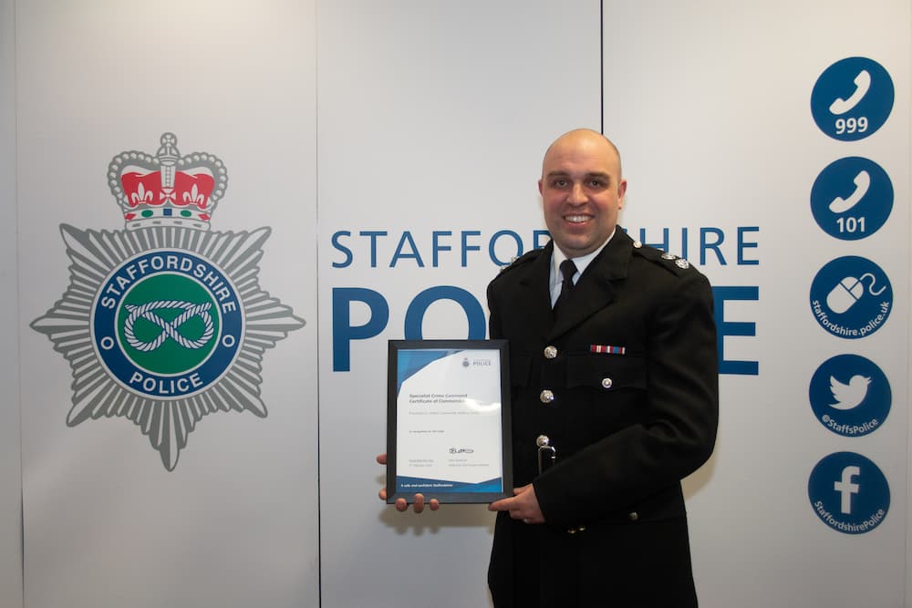 Watch Commander Andrew Huckle, photographed holding a certificate infront of a Staffordshire Police branded board